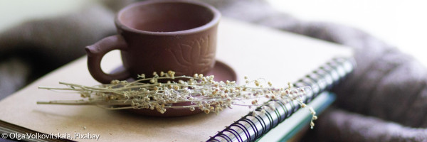 Bücherstapel mit Kafeetasse und Blumen