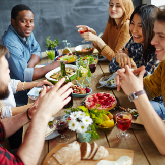 Junge Menschen sitzen am gedeckten Tisch und essen