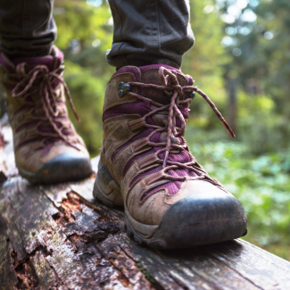 Eine Person mit Wanderschuhen läuft über einen Baumstamm