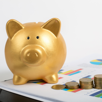Goldenes Sparschwein und Münzen auf Tisch
