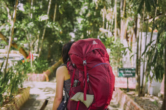 Junge Frau mit Backpacking-Rucksack zwischen Palmen